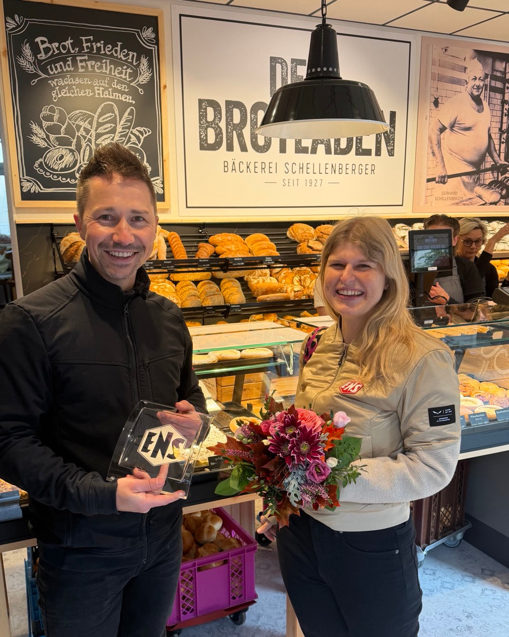 Bianca Mann von ENS Ladenbau Glauchau überreicht Blumen zur Wiedereröffnung von DEIN Brotladen an Chef Alexander Schellenberger.